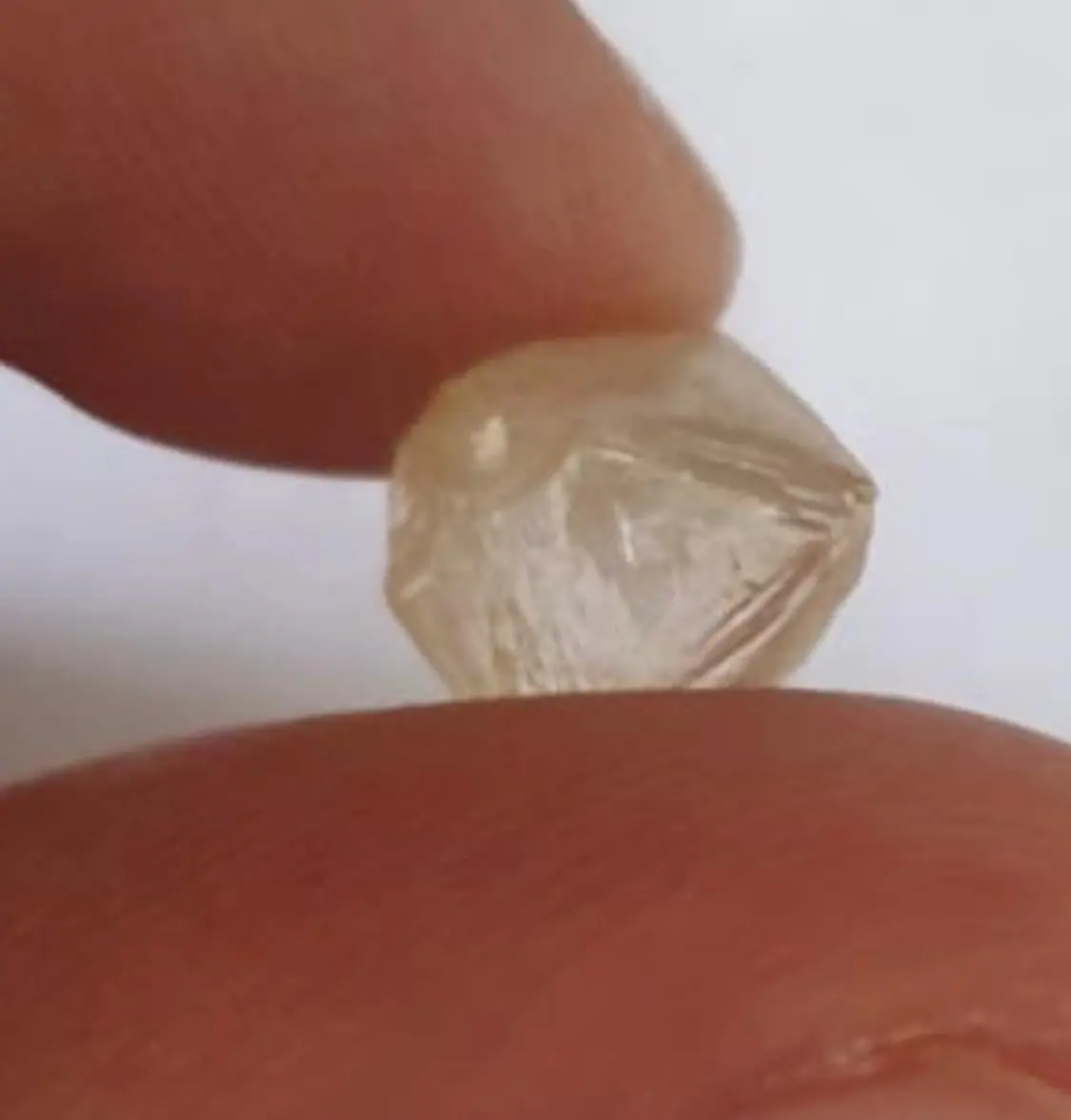 Octaèdre de diamant brut angolais tenu entre les doigts