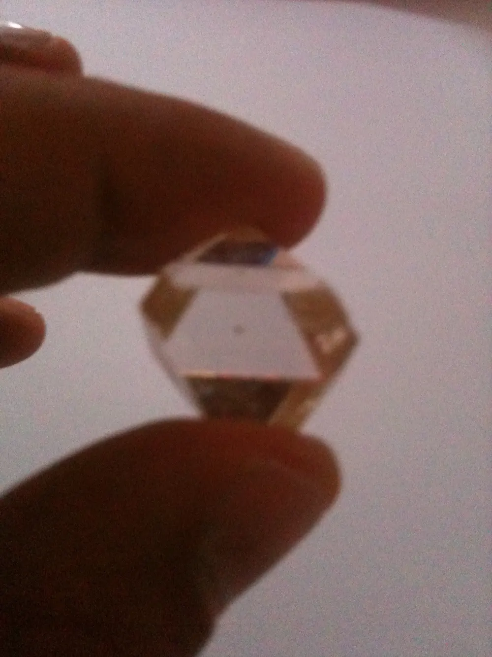 Diamant brut cristallisé tenu entre deux doigts