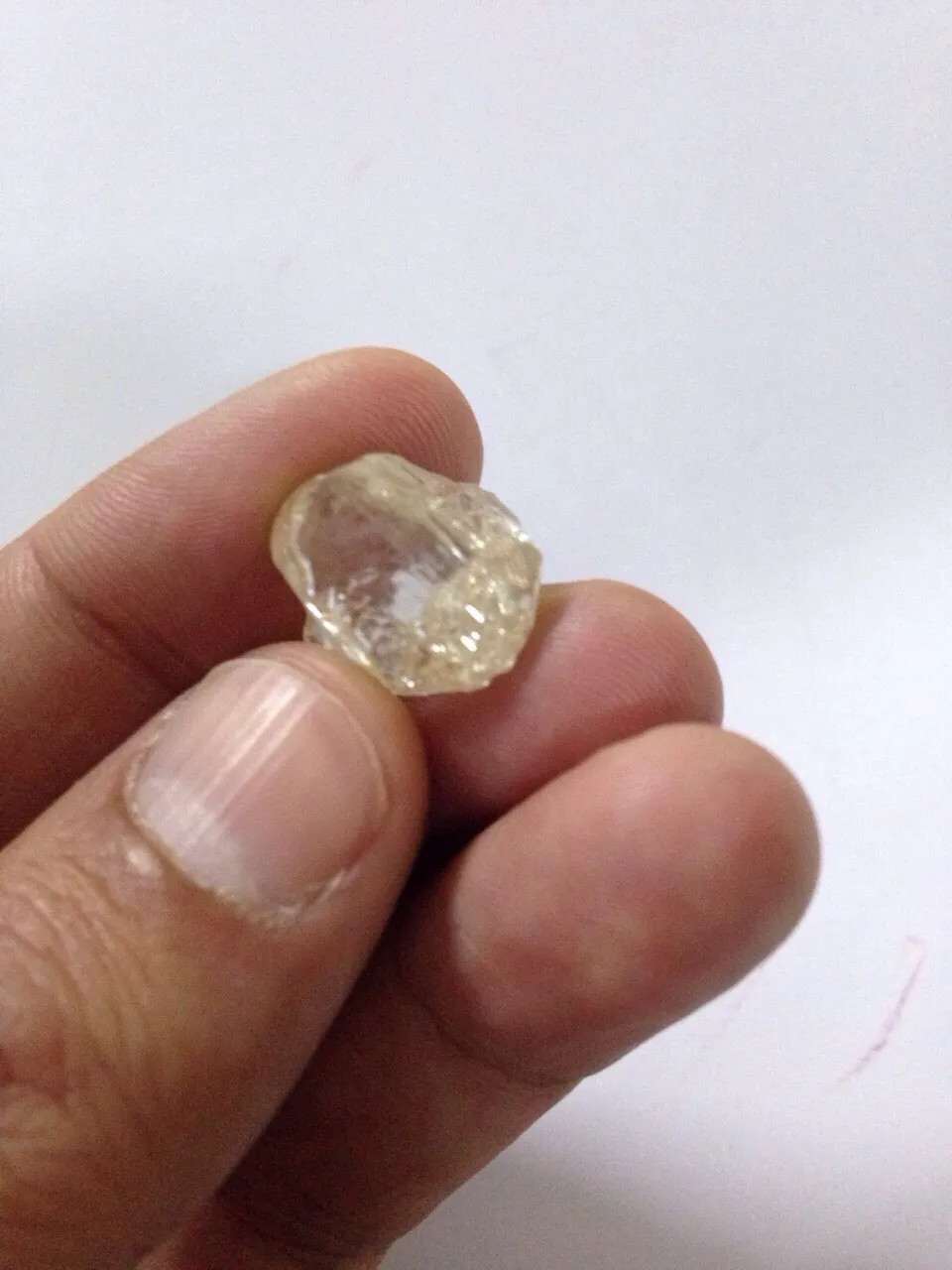 Diamant brut tenu entre les doigts